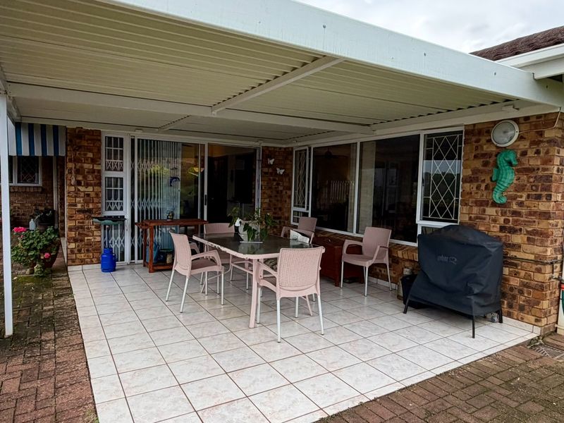 A covered outdoor patio area featuring tiled flooring and direct access to the interior through sliding glass doors, set against a brick townhouse facade.