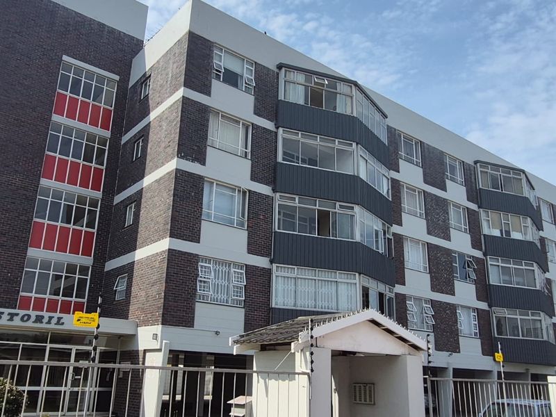 Exterior view of the Estoril apartment building featuring a multi-story brick facade with security fencing and integrated window units.