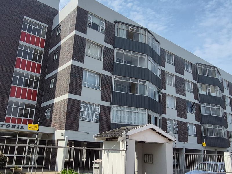 Exterior view of the Estoril apartment building featuring a multi-story brick facade with integrated balconies and security fencing.