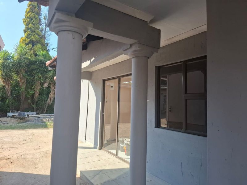 A covered patio area featuring concrete columns, tiled flooring, and a sliding glass door leading into the home.