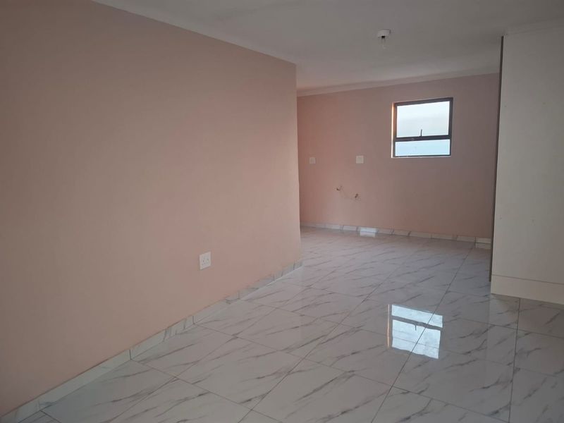 A bright, empty living area featuring modern marble-look floor tiles and neutral wall paint, providing a clean and versatile space.