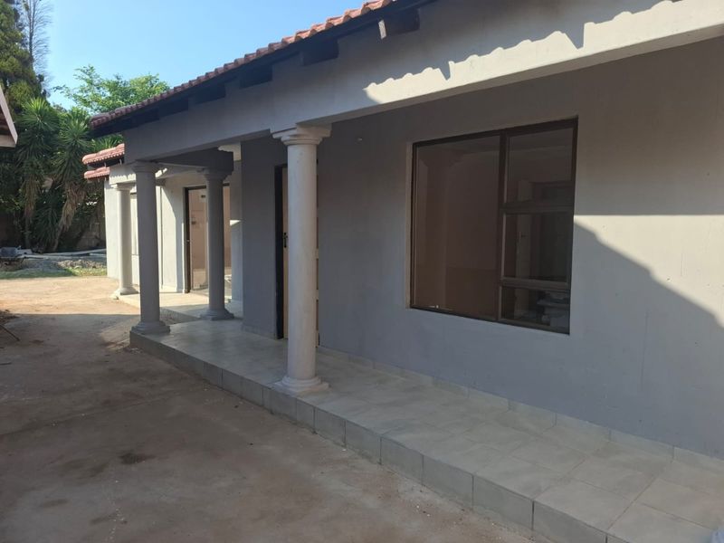 A covered patio area featuring tiled flooring and structural columns, providing a sheltered outdoor space adjacent to the main building structure.