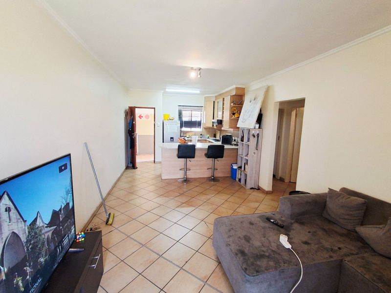 Open-plan living area featuring tiled flooring and a functional kitchen with a breakfast counter, providing a versatile space for dining and relaxation.