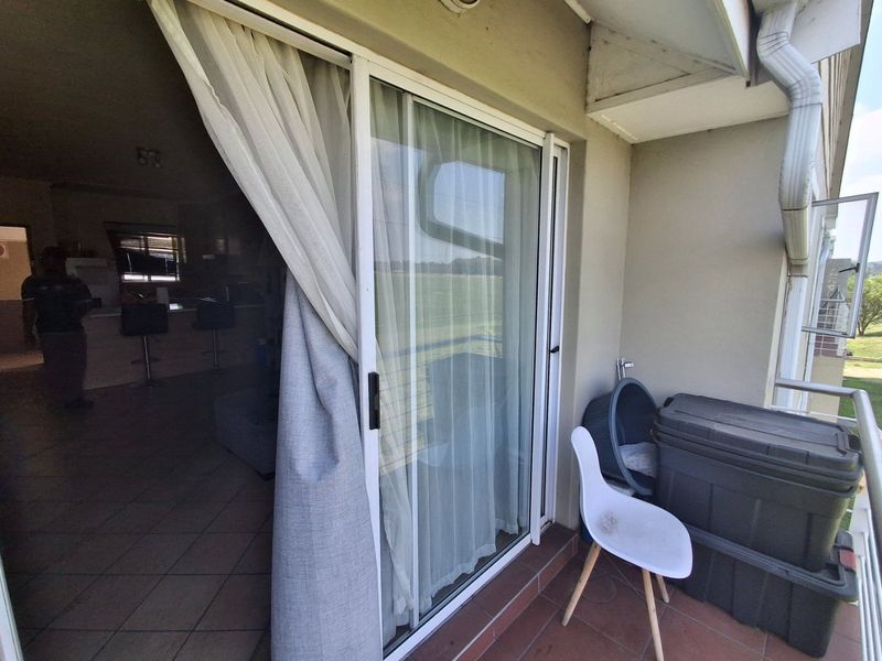 A covered balcony area featuring tiled flooring and a sliding glass door providing access to the interior living space.