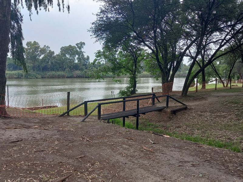 A scenic view of a lake featuring a small wooden footbridge and natural landscaping, providing a tranquil outdoor setting.