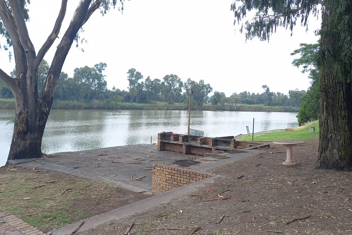 Outdoor riverside area featuring a brick built-in braai and concrete patio, offering direct access to the water.