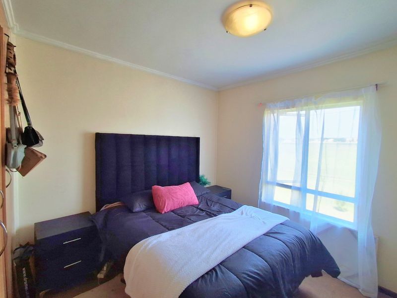 A standard bedroom featuring a large window and a central ceiling light fixture.