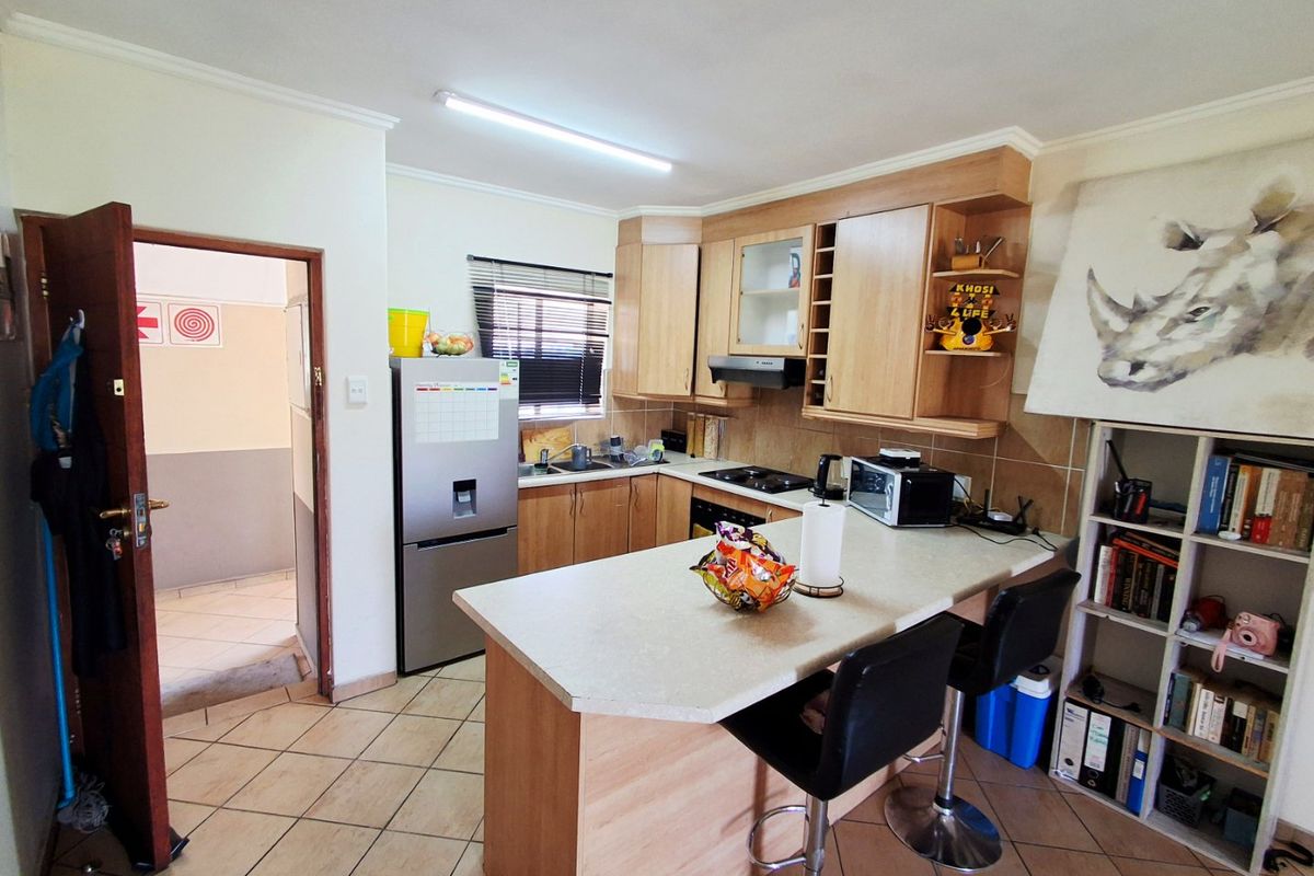A functional kitchen featuring light wood cabinetry, laminate countertops, a breakfast bar, and tiled flooring, providing a practical layout for daily use.