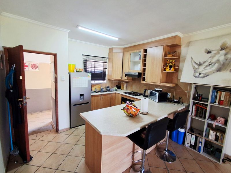 A functional kitchen featuring light wood cabinetry, laminate countertops, a breakfast bar, and tiled flooring, providing a practical layout for daily use.