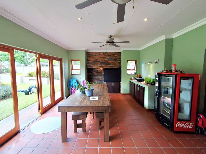 Spacious covered patio featuring terracotta flooring, built-in braai with stone cladding, and large wooden folding doors opening to the garden.