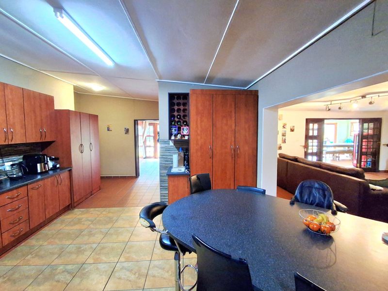 Open-plan kitchen and dining area featuring wood-finish cabinetry, tiled flooring, and a built-in wine rack, flowing into the adjacent living space.