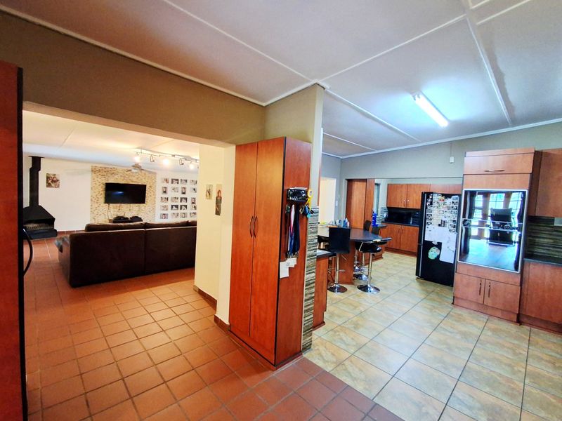 Open-plan living and kitchen area featuring tiled flooring, built-in cabinetry, a breakfast bar, and a fireplace in the lounge section.