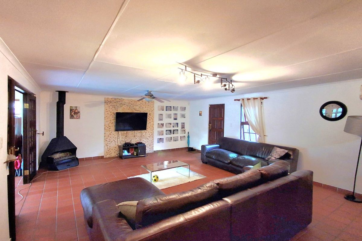 Spacious living room featuring a stone accent wall, a freestanding fireplace, tiled flooring, and a ceiling fan.