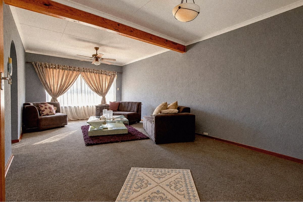 Spacious living room featuring a textured wall finish, exposed timber ceiling beam, and a ceiling fan, providing a comfortable and functional living space.