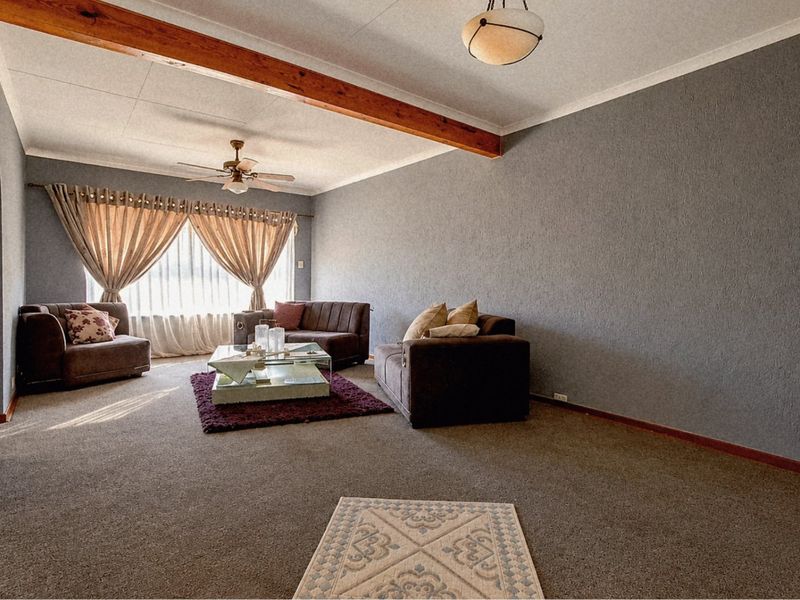 Spacious living room featuring a textured wall finish, exposed timber ceiling beam, and a ceiling fan, providing a comfortable and functional living space.