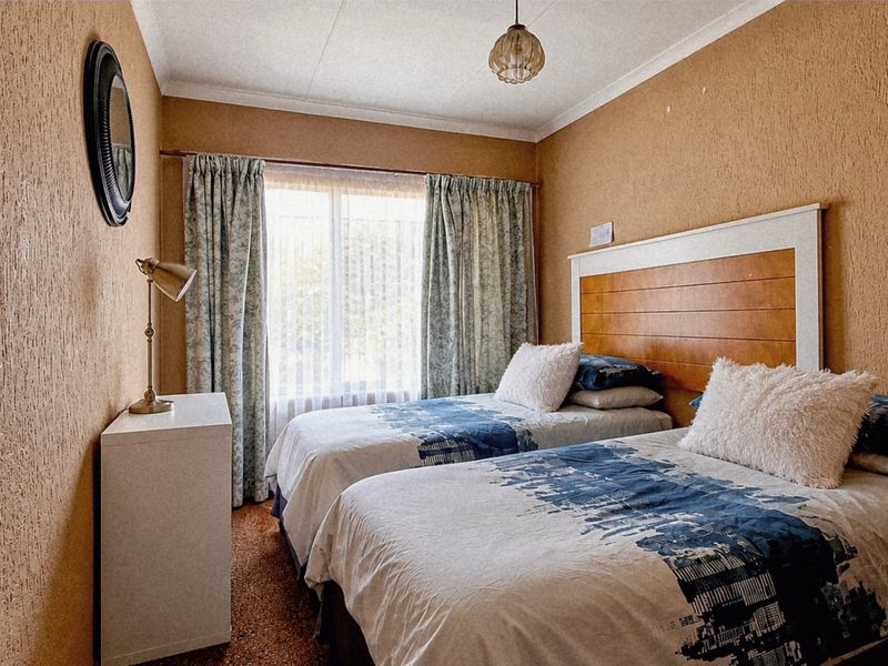 A bedroom featuring textured wall finishes, a built-in headboard, and natural light through a window with curtain rails.