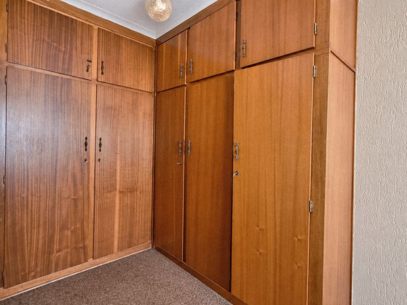 A bedroom featuring extensive floor-to-ceiling built-in wooden cabinetry and carpeted flooring.