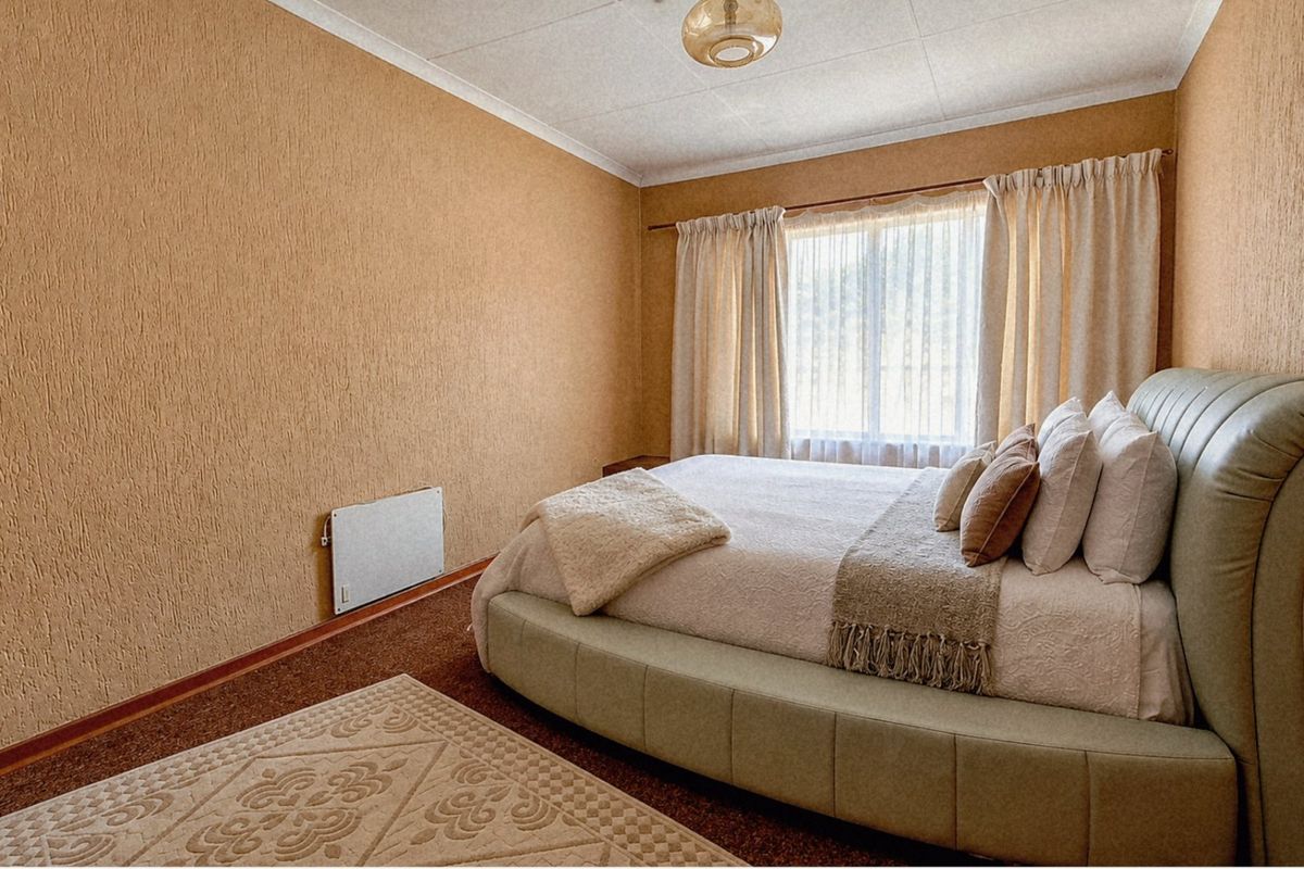 A bedroom featuring textured wall finishes, a wall-mounted electric heater, and a coved ceiling, providing a functional and dated living space.
