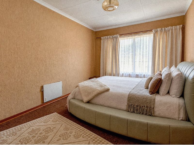 A bedroom featuring textured wall finishes, a wall-mounted electric heater, and a coved ceiling, providing a functional and dated living space.