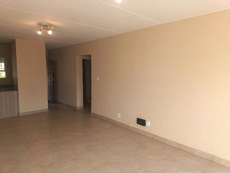 An open-plan living area featuring neutral textured walls and tiled flooring, providing a blank canvas for interior design and furniture placement.