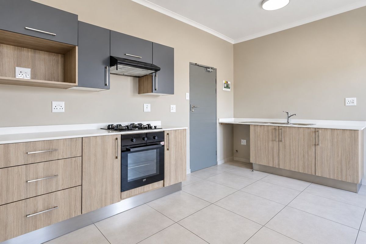 Modern kitchen featuring light wood-grain cabinetry, contrasting grey upper cabinets, stone countertops, built-in gas hob, electric oven, and tiled flooring.