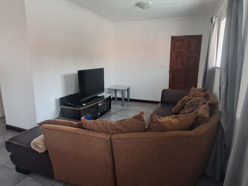 Open plan living area featuring tiled flooring and neutral walls, providing a functional space that connects to the kitchen area.