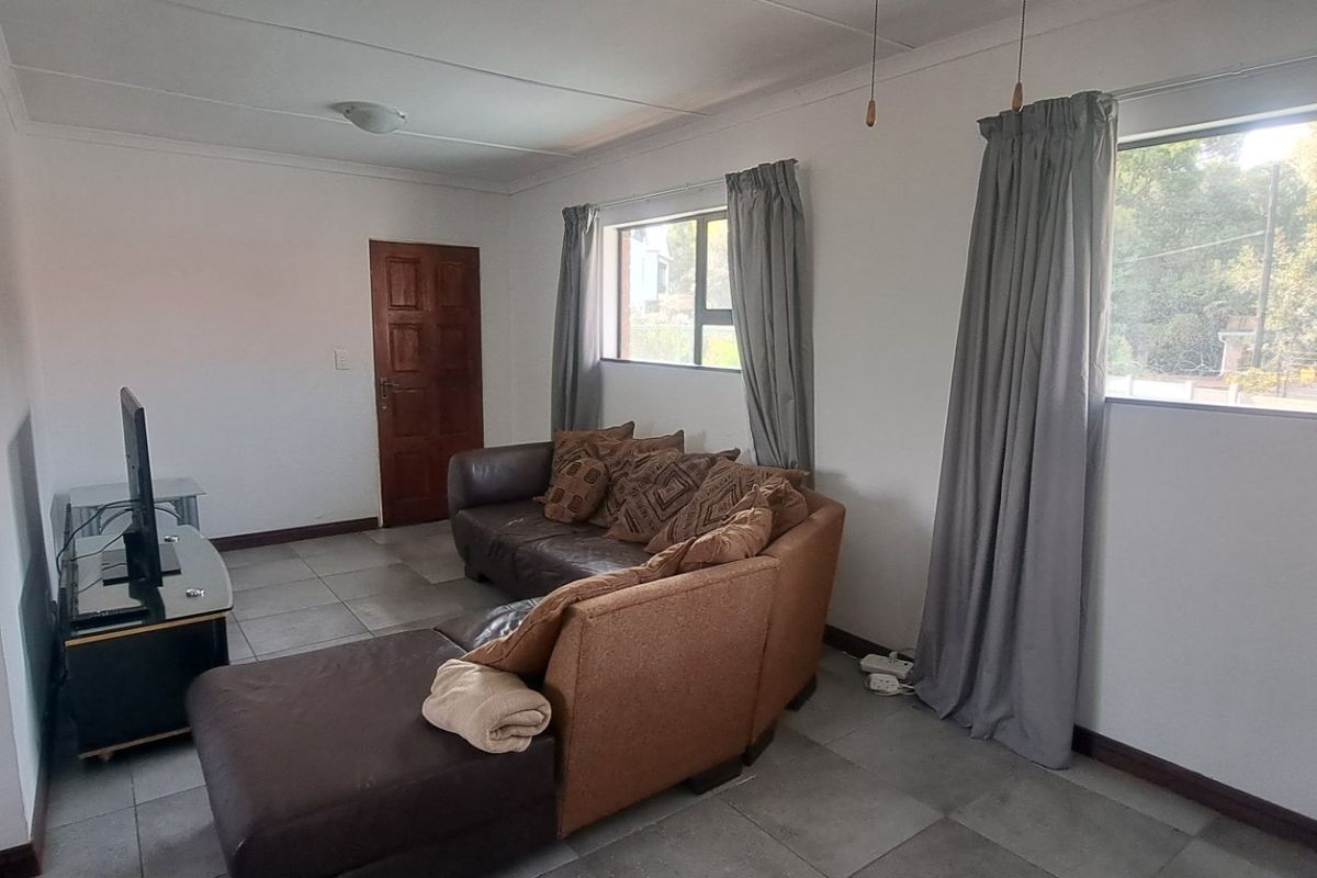A functional living room featuring tiled flooring, large windows with natural light, and neutral wall finishes.