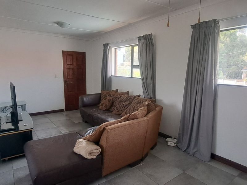 A functional living room featuring tiled flooring, large windows with natural light, and neutral wall finishes.