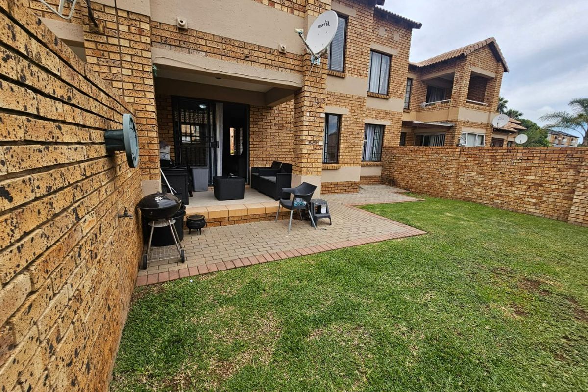 Rear view of the apartment featuring a private paved patio area, face brick exterior, and a small enclosed garden space.