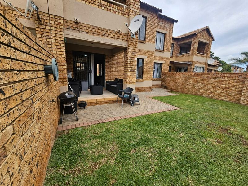 Rear view of the apartment featuring a private paved patio area, face brick exterior, and a small enclosed garden space.