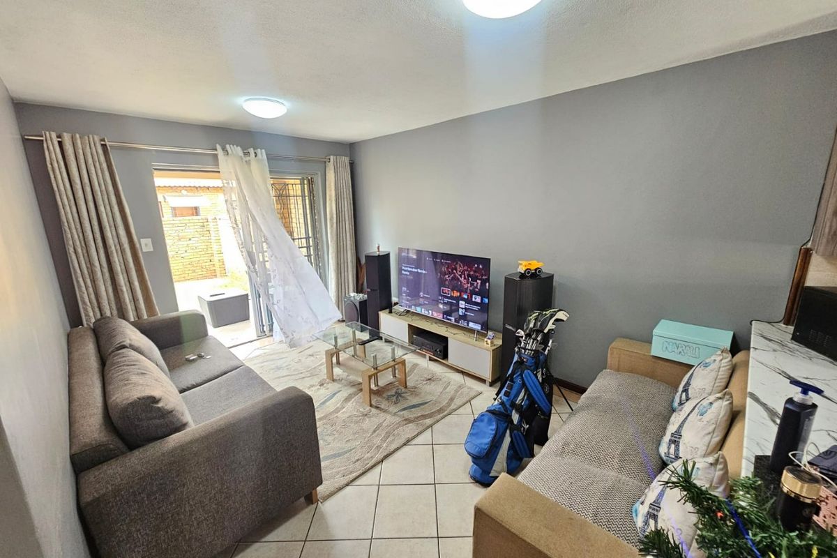 A living room featuring tiled flooring and a sliding glass door providing access to an outdoor area.