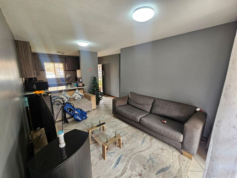 Open plan living area featuring tiled flooring and a functional kitchen with breakfast bar, providing a versatile space for daily living and dining.