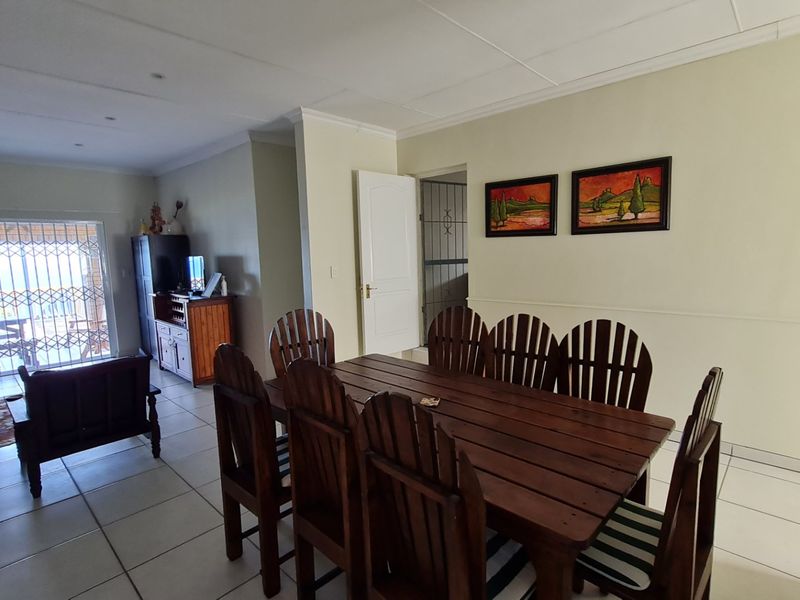 Open plan living and dining area featuring tiled flooring, recessed ceiling lights, and access to an outdoor patio through a secure sliding door.