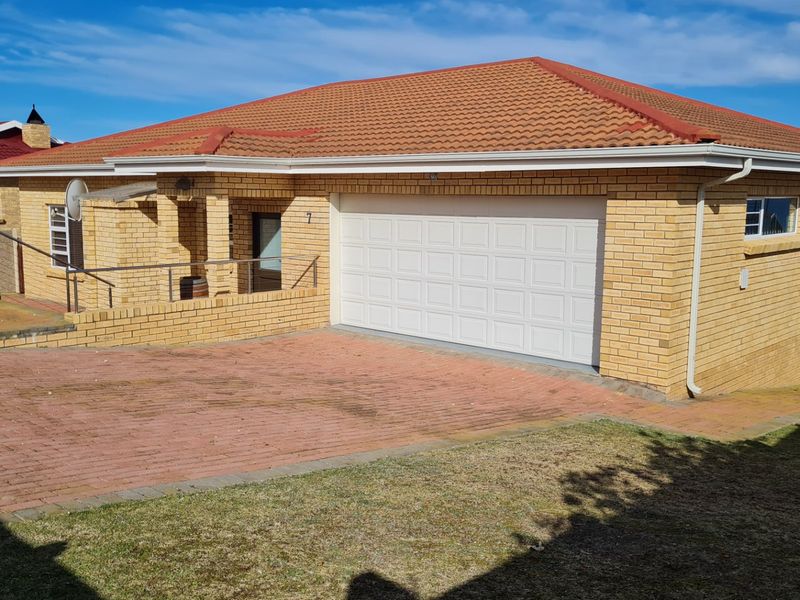Front view of a brick house featuring a tiled roof, paved driveway, and a double garage entrance.