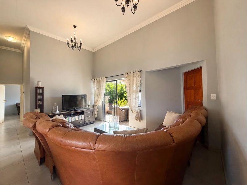 Spacious living room featuring high ceilings, tiled flooring, and a sliding glass door providing access to the outdoor patio area.