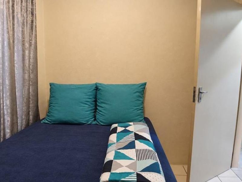 A functional bedroom featuring neutral wall finishes, tiled flooring, and an internal door leading to the hallway.