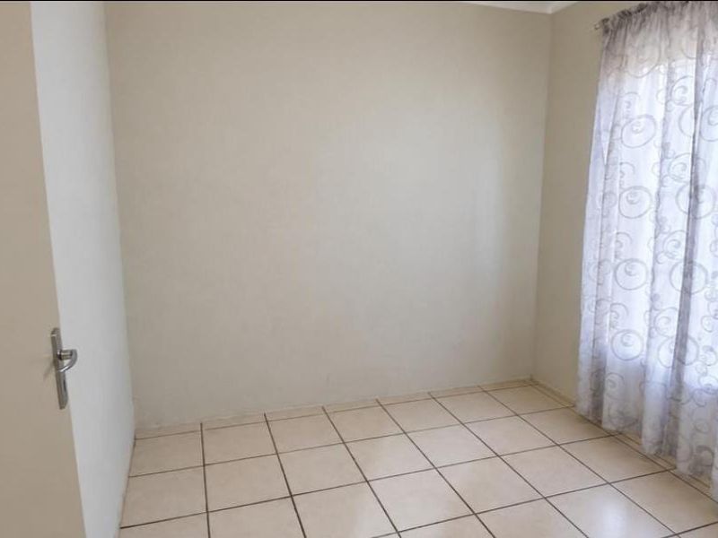 A simple, empty bedroom featuring neutral wall paint and tiled flooring, providing a blank canvas for personalization.