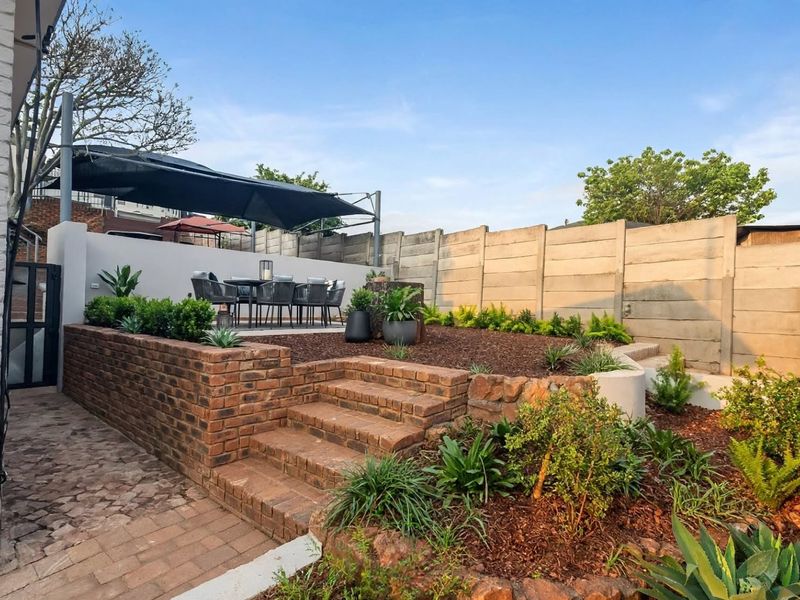 A well-maintained terraced garden featuring brick retaining walls, paved pathways, and established garden beds, providing a structured outdoor space.