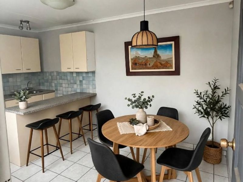 Open plan kitchen and dining area featuring tiled flooring, breakfast bar seating, and neutral cabinetry with a tiled backsplash.