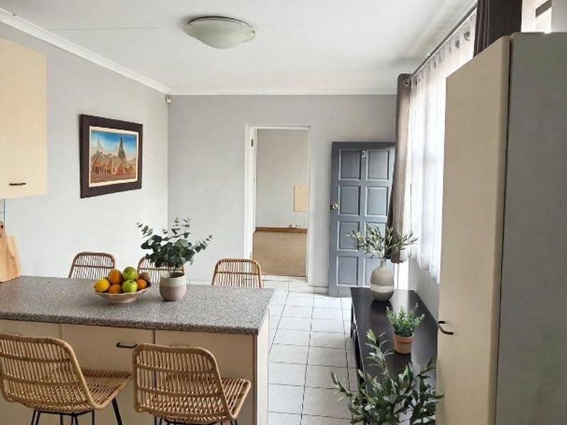 Open plan kitchen and dining area featuring a central island with granite countertops, tiled flooring, and neutral wall finishes.