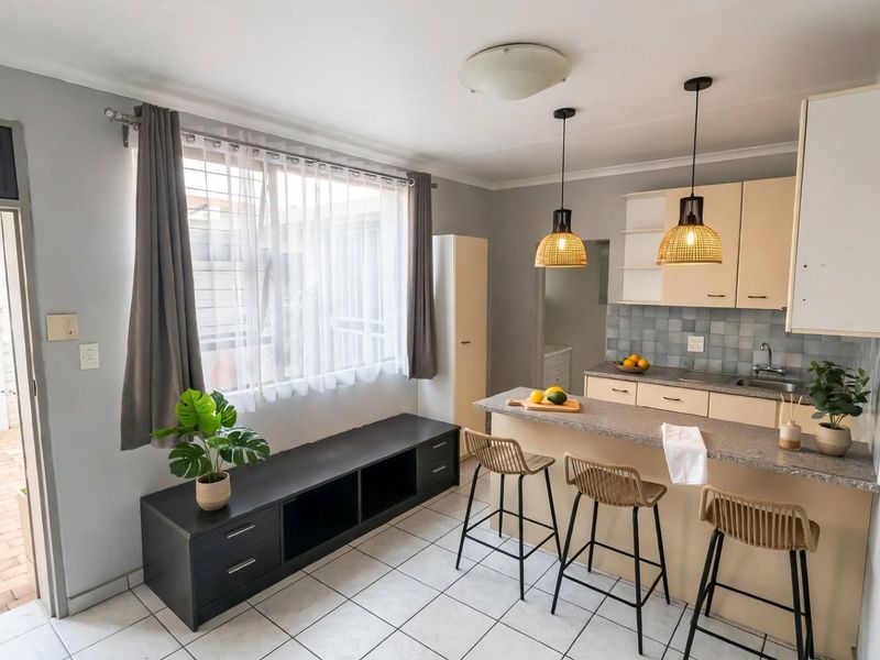 Open-plan kitchen and living area featuring tiled floors, neutral cabinetry, stone countertops, and direct access to an outdoor patio space.