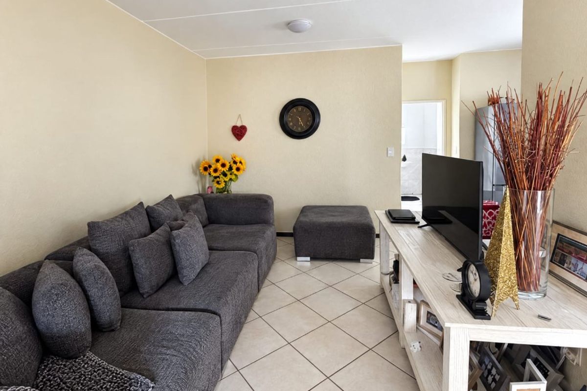 A comfortable living room featuring neutral wall tones and light-colored tiled flooring, providing a functional and well-lit space.