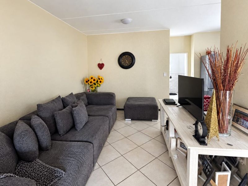 A comfortable living room featuring neutral wall tones and light-colored tiled flooring, providing a functional and well-lit space.