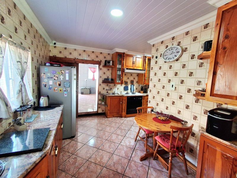 A functional kitchen featuring wooden cabinetry, stone-look countertops, built-in cooking appliances, and tiled finishes throughout.