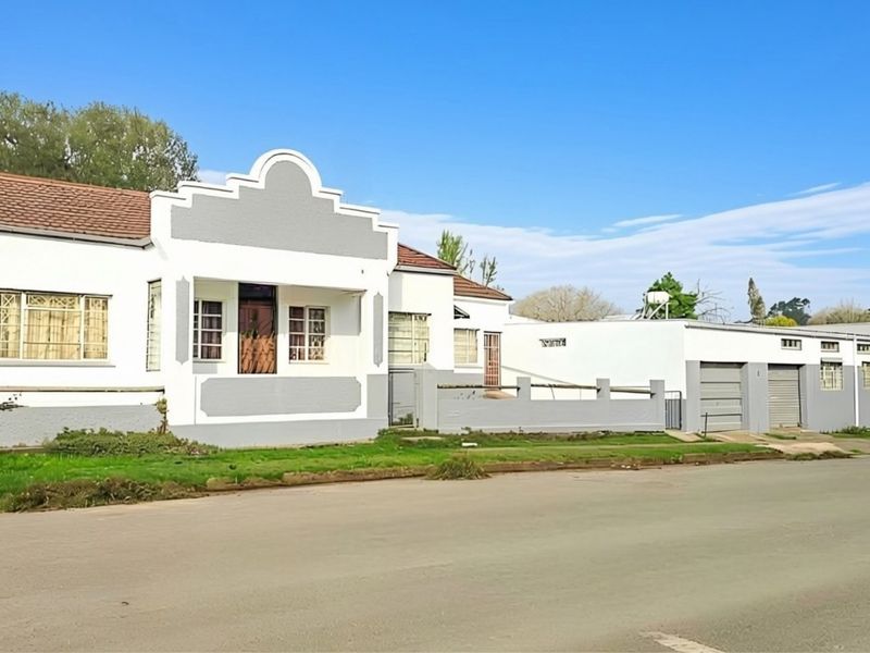 Front elevation of a single-story house featuring a distinctive gabled facade, attached garage, and perimeter boundary wall.