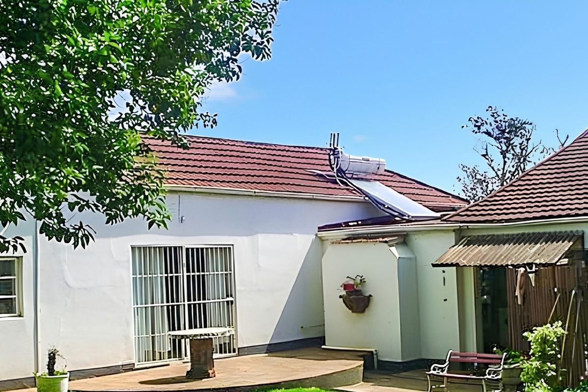 Rear view of the house featuring a tiled roof with a solar water heater, a concrete patio, and sliding door access.