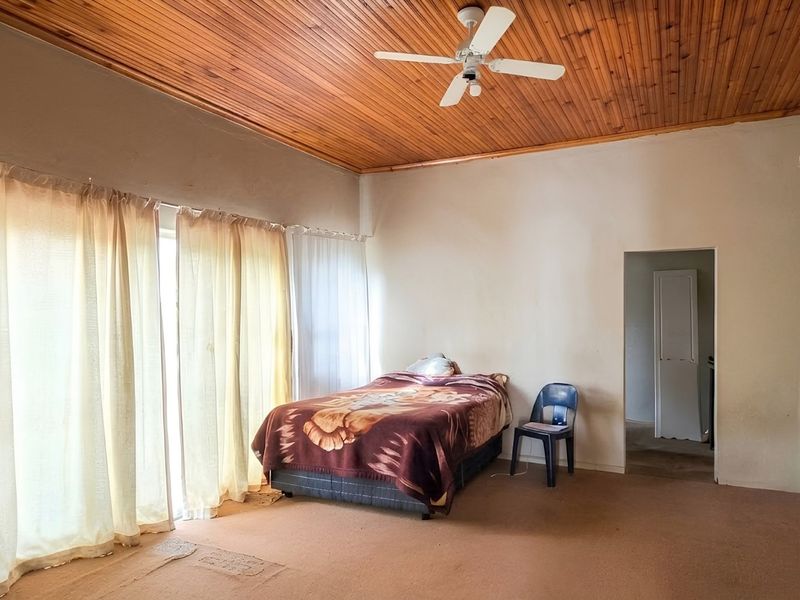 Spacious bedroom featuring a warm timber tongue and groove ceiling, ceiling fan, and sliding glass door access to the exterior.