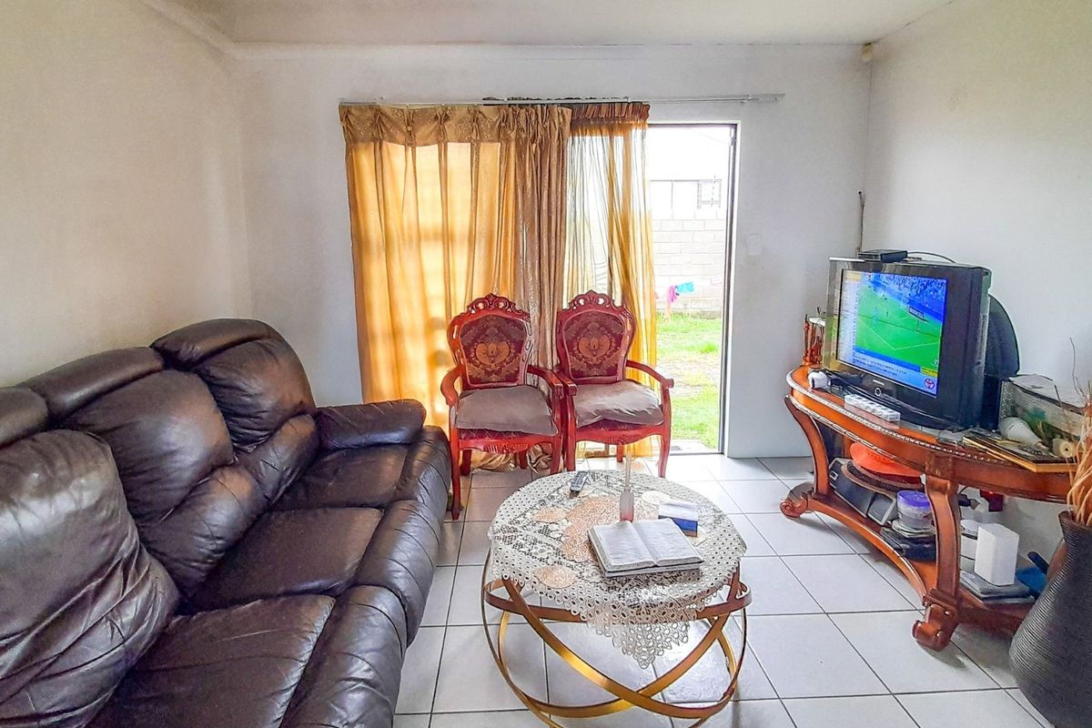 A functional living room featuring tiled flooring and a sliding glass door providing direct access to the rear garden area.