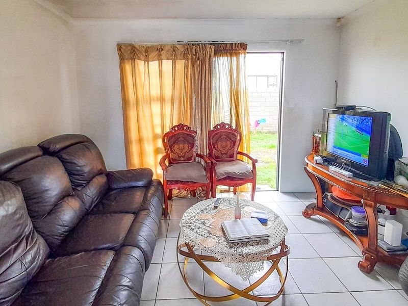 A functional living room featuring tiled flooring and a sliding glass door providing direct access to the rear garden area.