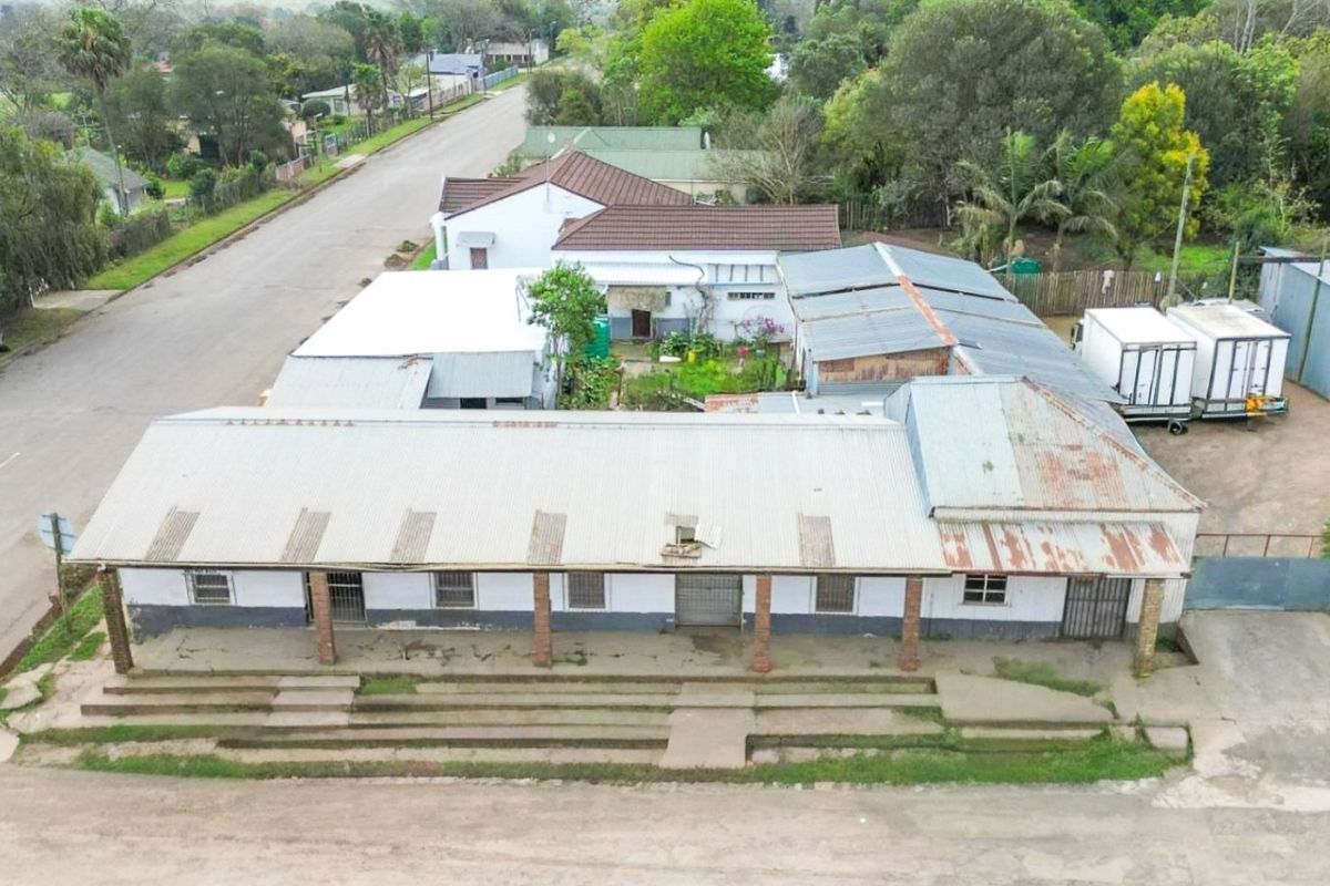 Aerial view of a commercial property featuring a long structure with corrugated metal roofing, brick pillars, and concrete steps.